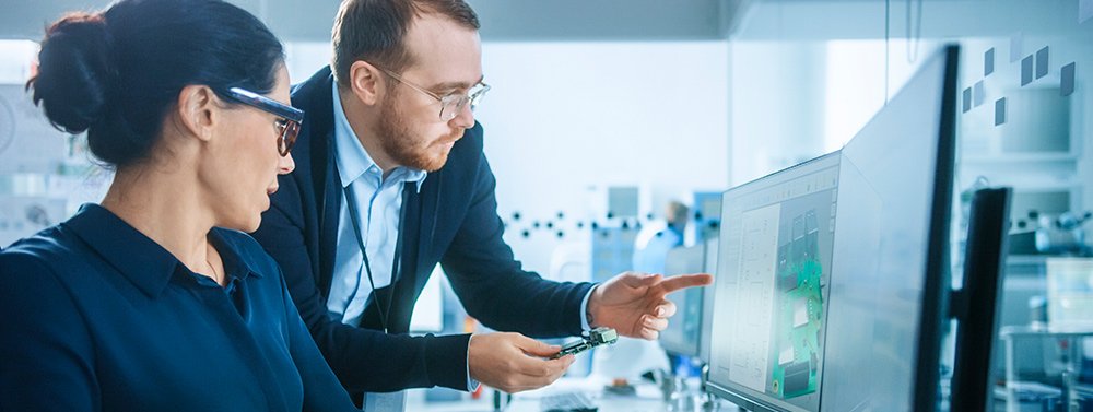 ciberseguridad-certificacion-kit-consulting Dos personas hablando y mirando a una pantalla de ordenador. Servicio de Ciberseguridad para obtener certificación del Kit Consulting